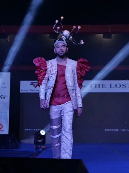 A model in a creative outfit with exaggerated red sleeves and a unique headpiece.