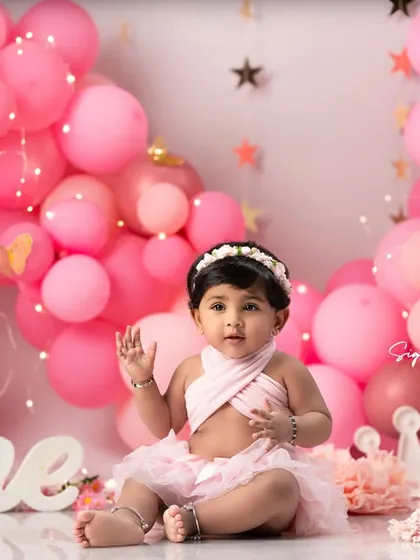 Waving hello to being one year old! This shot showcases the adorable pink outfit and floral headband that are part of the styling I provide for these sessions.