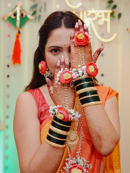 A playful portrait of the bride peeking through her hands during her Haldi ceremony.