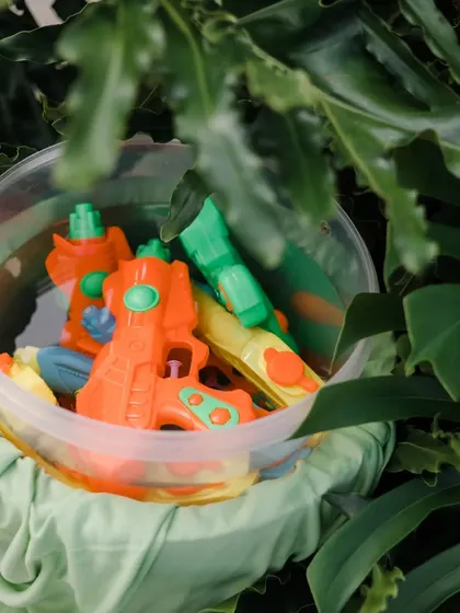 A bucket of water guns, ready for a fun and playful pool party to kick off the wedding celebrations.