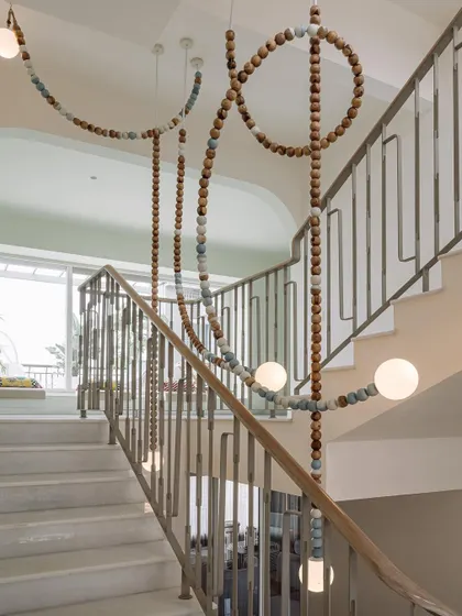 The 'Luna' light installation at Eden House is a bold, meandering fixture made of wooden beads that depicts the phases of the moon. It transforms the stairwell into a visually intriguing art piece.
