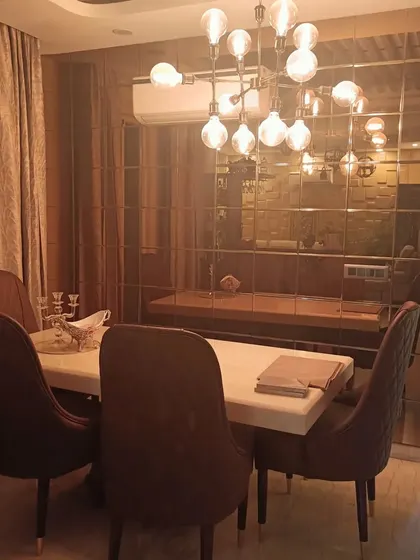 The dining area of the Bohemian home, featuring a wall of tinted mirrors that visually expands the space. The modern chandelier adds a touch of glamour to the eclectic design.