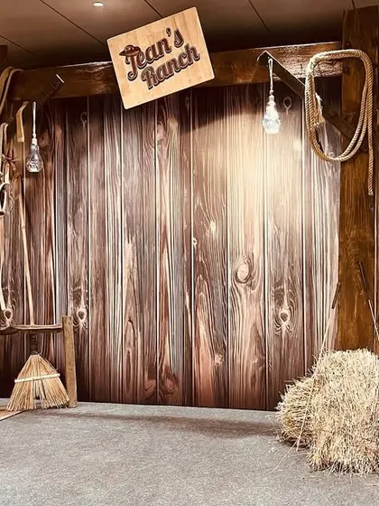 Giddy up! We created a rustic 'Ranch' themed photo booth with a wooden barn backdrop, hay bales, saddles, and ropes. This unique theme was perfect for a fun and informal get-together.
