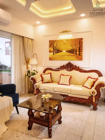 This living room features a classic carved wooden sofa that exudes traditional elegance. The design is balanced with modern touches like soft lighting and contemporary art for a perfect fusion.