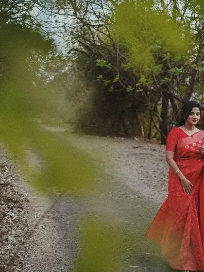 A wide shot of a woman in a red saree on a country road, with a dreamy, slightly blurred effect adding to the artistic mood.