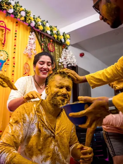 A moment of shared joy as multiple family members participate in applying Haldi to a smiling relative.