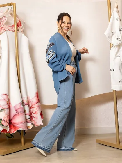 Deanne Panday looking effortlessly stylish. Her hair is pulled back into a casual but chic ponytail, complementing her fashionable denim ensemble.