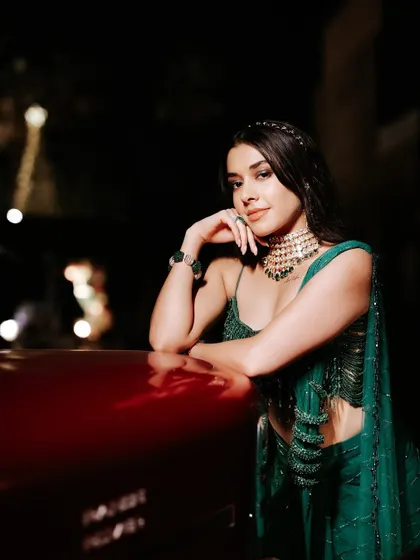 A modern and chic sangeet look. The bride's emerald green outfit is paired with soft, luminous makeup and sleek hair, creating a look that is both stylish and timeless.