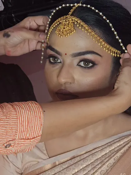 A behind-the-scenes shot of me placing the nethi chutti on a model for a traditional bridal look.