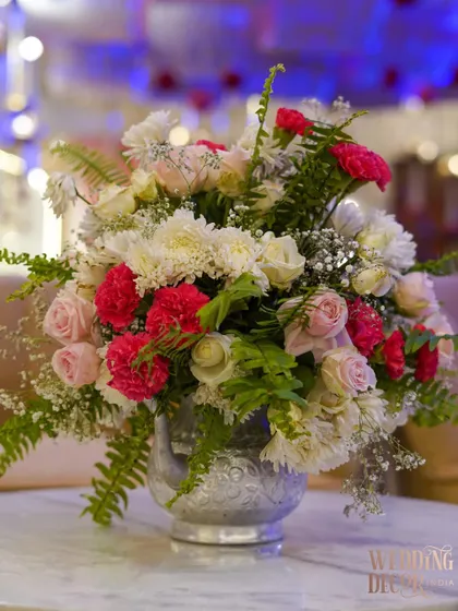 A simple yet beautiful arrangement of white and red carnations with ferns in a silver-etched vase. This kind of arrangement is perfect for adding a touch of elegance to cocktail tables.