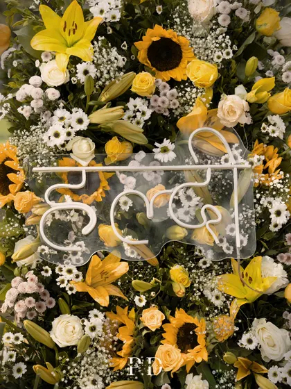 A custom neon 'Haldi' sign in Hindi, set against a backdrop of sunflowers and yellow lilies. It's a modern twist on a traditional element.