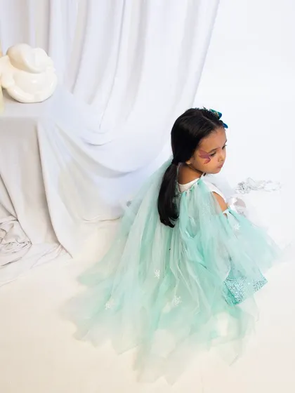 A high-angle shot of a child in a beautiful light-green fairy costume.
