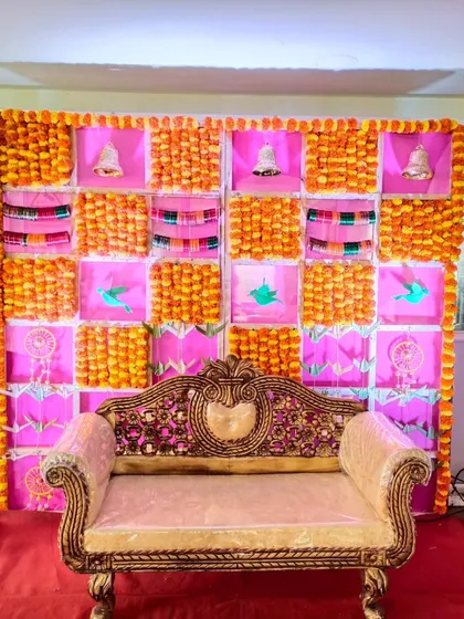 This is a traditional baby shower backdrop I created using a grid of pink fabric and bright orange marigold flowers. The classic sofa provides a perfect spot for the mother-to-be during the ceremony.