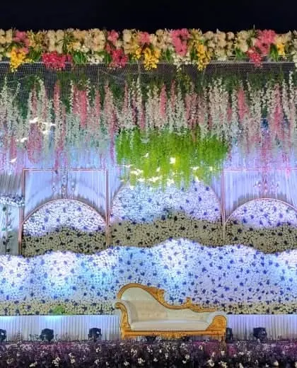 An ethereal reception stage design with waves of white flowers, hanging floral strings, and soft lighting, perfect for a dreamy and elegant evening celebration.