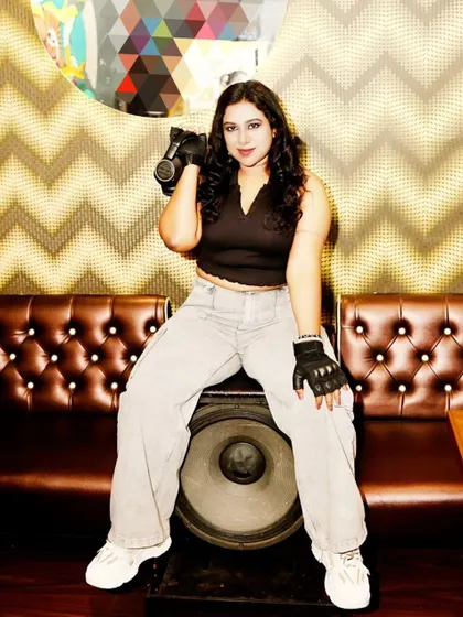 Sitting on a giant speaker, holding my headphones. This powerful pose is about owning the stage and being one with the sound system.