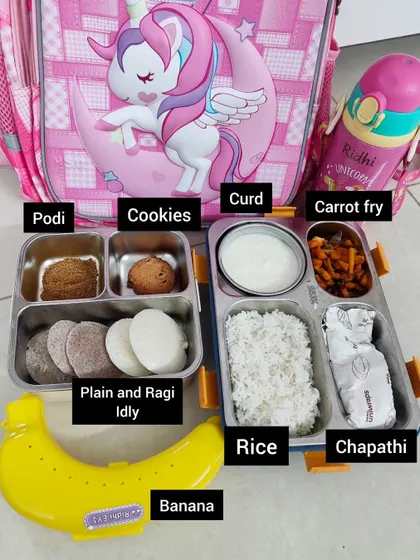 Another balanced meal idea for the tiffin box. This meal contains plain and ragi idly for breakfast, and for lunch, rice with carrot fry, chapathi, and curd. A banana and cookies are included for snacks.