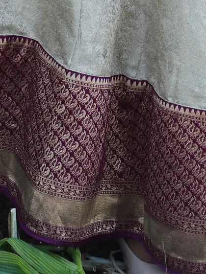 This image shows the heavy brocade border at the bottom of the skirt, featuring an intricate woven pattern in purple and gold.