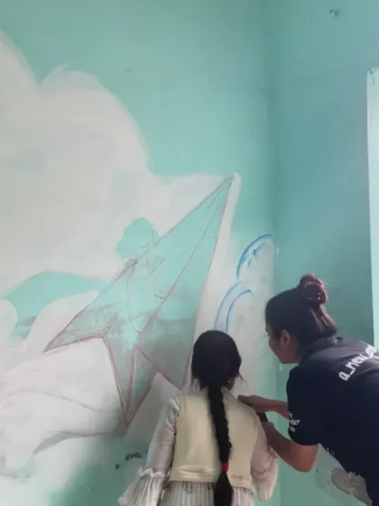 A quiet moment of collaboration during the Sonipat mural project. I am guiding one of the younger participants as she adds her touch to a paper plane flying through the clouds. It's in these small interactions that the real magic of community art happens.