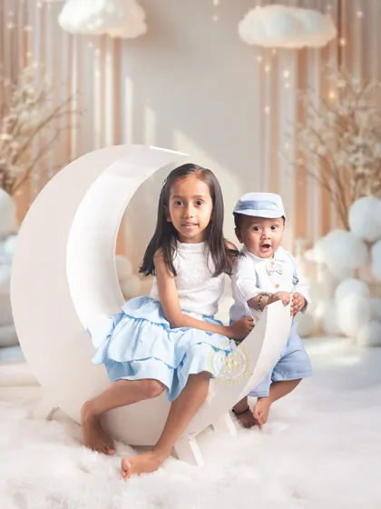 A whimsical themed photoshoot for siblings in our studio. We have a variety of props and creative setups, like this dreamy moon and clouds theme, to capture the magic of childhood and the special bond between siblings.