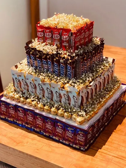 For the ultimate chocolate lover, we built this four layer chocolate tower. It's constructed from layers of Dairy Milk, Cadbury 5 Star, Snickers, and KitKats, and decorated with Ferrero Rochers and baby's breath.