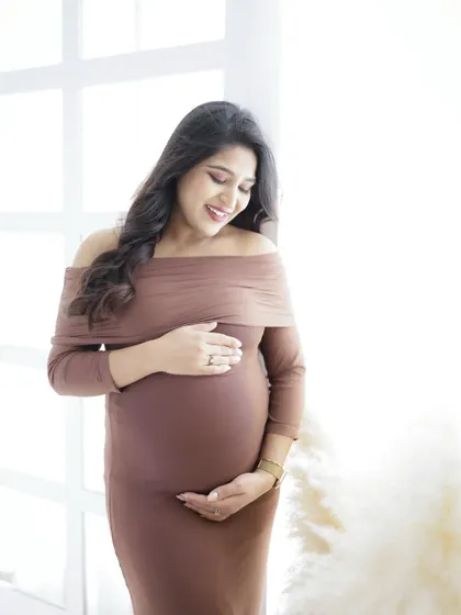 A simple and elegant portrait by the window. The mom-to-be's brown dress and the soft natural light create a warm and beautiful image.