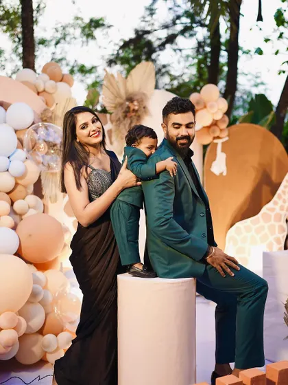 A candid shot of the family enjoying their son's first birthday celebration. The soft, neutral tones of the safari theme create a warm and inviting atmosphere.