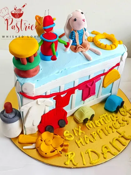 A half-birthday cake designed to look like a toy box, with lots of edible baby toys for a six-month celebration.