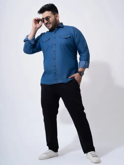 A stylish catalogue shot of a model in a denim shirt and black trousers. This image is perfect for a brand's website, showcasing a complete look.