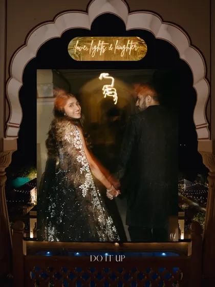 A romantic, artistic shot of the couple, framed by the venue's architecture and a custom neon sign. This image captures the magical, celebratory mood of the sangeet.