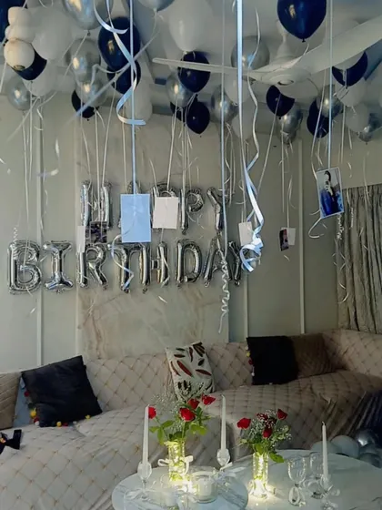 Another angle of the romantic birthday room setup, showing the 'Happy Birthday' foil balloons and photos hanging from the ceiling with ribbons.