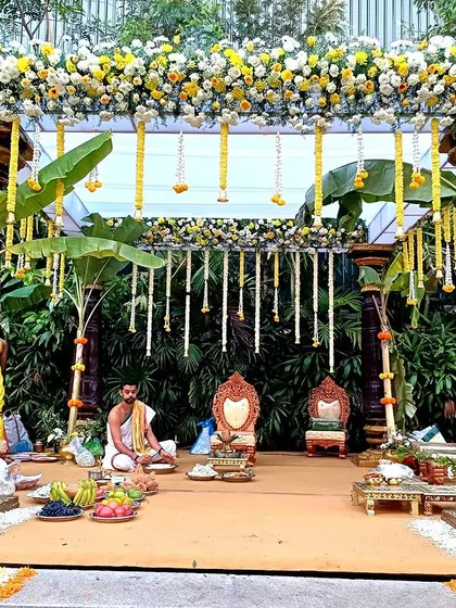 A traditional South Indian mandap setup with banana plants, marigold garlands, and ritual offerings.