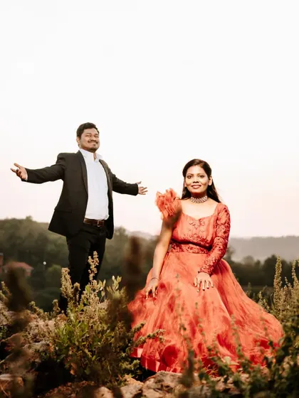 A joyful and dynamic maternity shoot in the hills. This red-orange gown with a unique sleeve design adds a vibrant pop of color to the natural scenery.