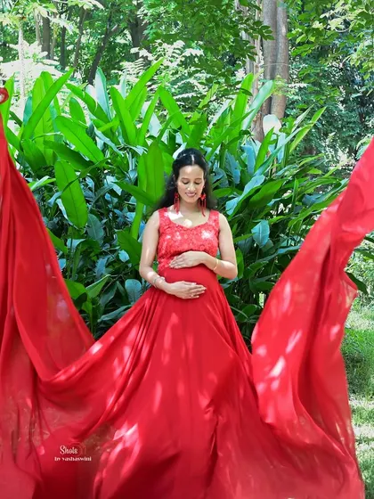 This red flying gown looks absolutely stunning for an outdoor maternity shoot. The long, flowing fabric creates a beautiful effect against the natural greenery.