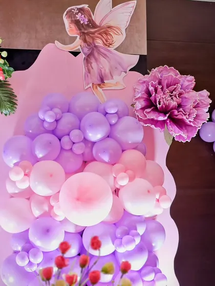 A beautiful arrangement of pink and purple balloons with a fairy cutout, part of a larger magical setup.