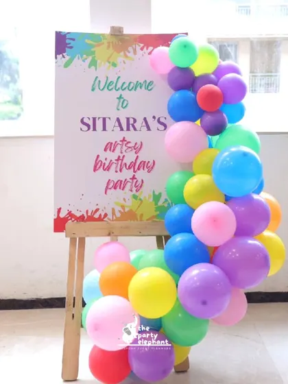 A personalized welcome sign for 'Sitara's artsy birthday party', decorated with a colorful balloon garland, set the creative tone for the event right from the entrance.