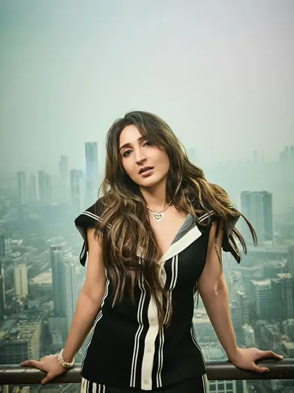 This pose creates a sense of relaxed confidence, as if she's on top of the world. The outfit is perfect for this modern, urban setting.