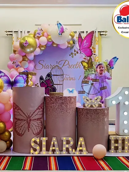 A lovely butterfly-themed first birthday with a photo of the birthday girl. The pink and gold balloon arch and butterfly details create a warm and celebratory feel.