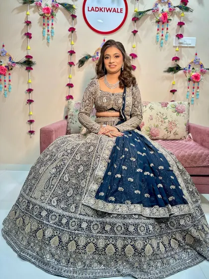 The bride is seated, showcasing her magnificent navy and silver lehenga for her sangeet ceremony.