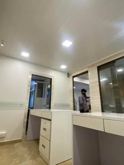 A wide view of a completed office for a Chartered Accountant client. This angle highlights the clean, open layout with custom-built modular desks, integrated drawers, and a modern PVC panelled ceiling with recessed LED lighting. The design focuses on creating a professional and efficient workspace.