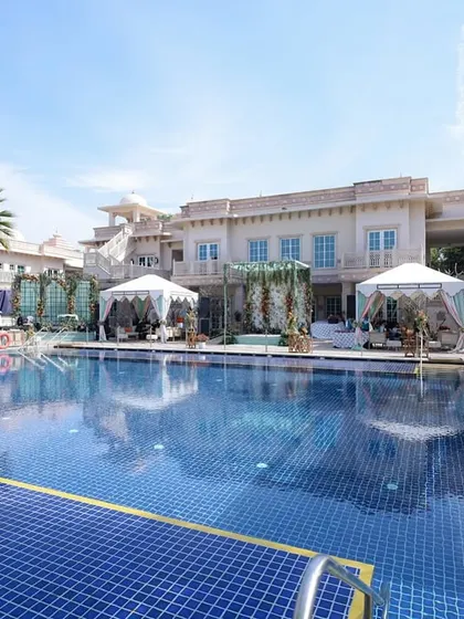 A wide shot of the beautiful poolside venue, showing the luxurious setup with draped canopies and comfortable lounge areas.