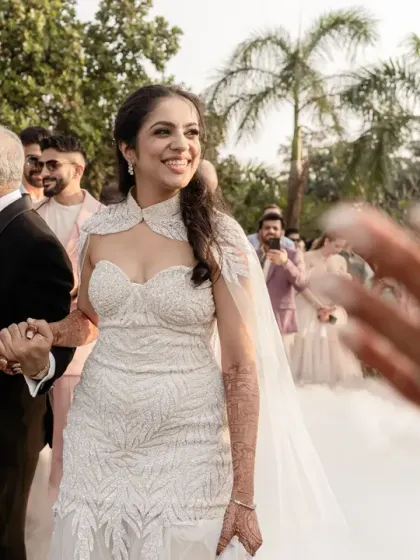 The bride's radiant smile as she walks down the aisle, with a guest's hand reaching out in a gesture of blessing. This shot beautifully captures the love and support from family and friends.