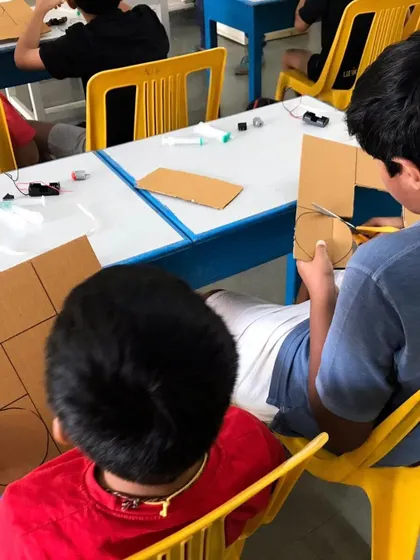 Students working together during a workshop, cutting out cardboard components for a project. We emphasize collaboration and peer-to-peer learning in our sessions.