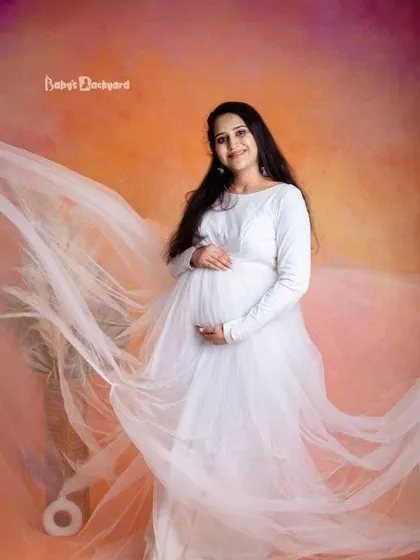 An angelic and dreamy portrait. The flowing white gown and soft studio lighting create a heavenly look for this beautiful mother-to-be.