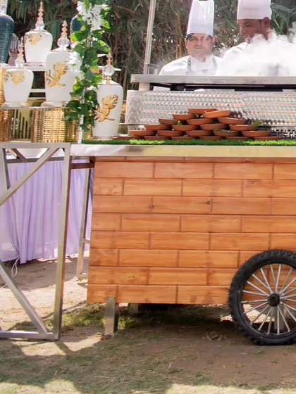 A chef preparing a dish with dramatic flair at a live station. The steam and action from the live cooking add an element of entertainment for guests at the event.