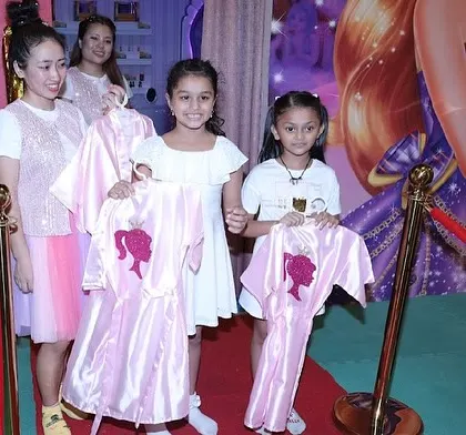 Girls proudly hold up their personalized pink spa robes before their pampering session begins.