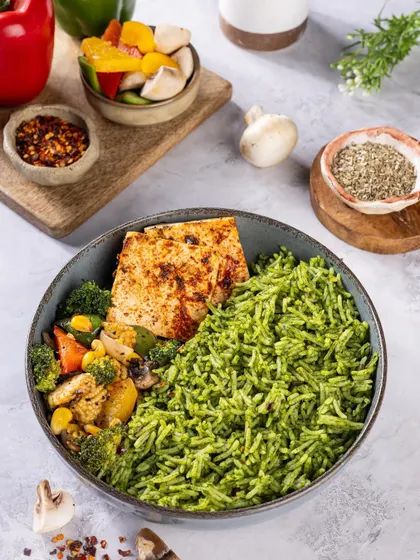 A healthy and vibrant meal bowl with green rice, grilled paneer, and sautéed vegetables, styled with fresh ingredients.