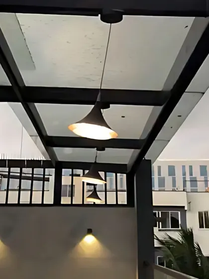 Pendant lights hang over an outdoor balcony, providing functional light while adding to the modern exterior design.