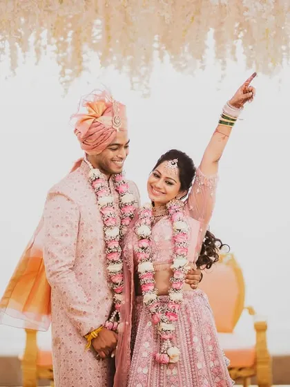 A candid, happy moment between the bride and groom at their beachside mandap. The bride points up in excitement, sharing a laugh with her new husband, a memory of pure joy.