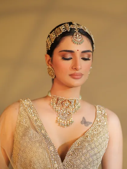 A serene, eyes-closed shot that focuses on the beautiful makeup and the intricate details of the jewelry.