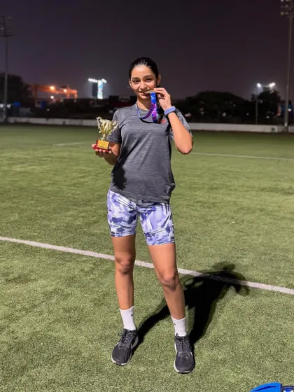 A full-length shot of Aayra with her trophy and medal on the track after her successful race. She crushed it.
